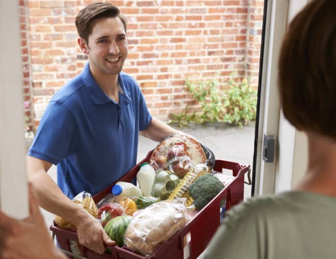 smiling delivery worker handing groceries to a customer