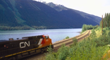 train on the tracks overlooking mountains and lake