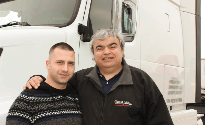 two smiling drivers in front of truck