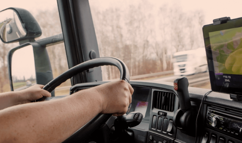 hands guiding steering wheel inside truck