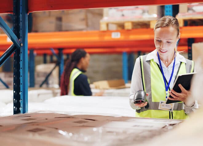 Woman scanning boxes in a warehouse.